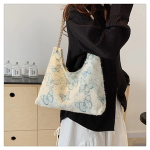 Close-up of butterfly print canvas tote bag with gold chain strap and frayed edge detail