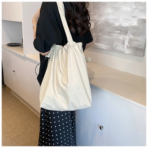 Detailed back view of a minimalist cream canvas tote bag with a drawstring closure and wide strap