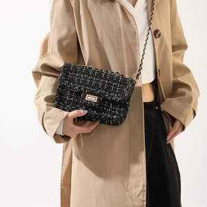 Elegante borsa a tracolla in tweed bianco e nero con fibbia dorata indossata da una modella