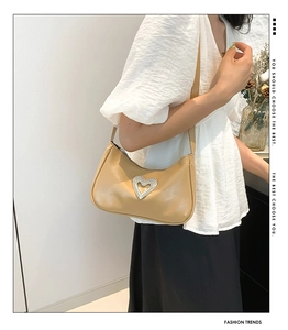 Detailed side view of beige PU underarm bag featuring a sparkling rhinestone heart