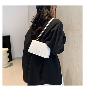 Détail d'un sac bandoulière blanc matelassé avec chaîne dorée et lettrage moderne
