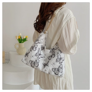 Detailed view of the large canvas tote bag featuring black butterfly prints and chain strap