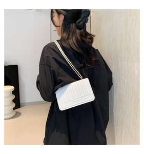 Sac bandoulière blanc matelassé verticalement avec détails de chaîne en métal doré