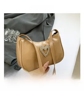 Close-up of heart-shaped diamond embellishment on khaki lychee texture baguette bag