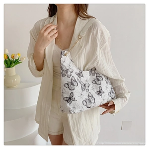 Detail of artistic black butterfly print on white tote bag with golden chain strap