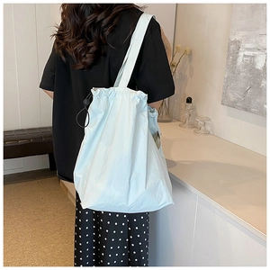 Close-up of light blue nylon tote bag with black drawstring closure detail on side