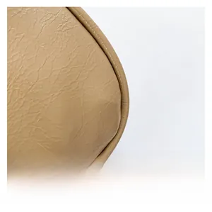 Macro shot of pleated synthetic leather texture and bottom corner stitching on beige bag