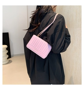 Détail du sac bandoulière rose clair avec matelassage vertical et bandoulière chaîne