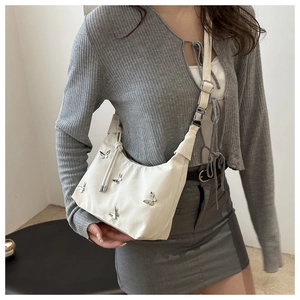 Detail of cream white dumpling bag featuring silver metallic butterflies and adjustable strap
