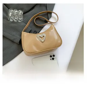 Close-up of khaki baguette bag with pleated texture and silver heart buckle detail