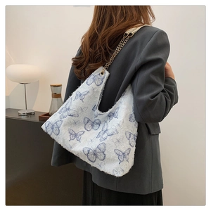 Dettaglio della borsa tote in peluche bianca con farfalle blu e tracolla a catena d'oro