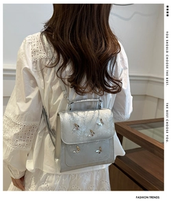 Close-up of a silver butterfly backpack featuring metallic accents and a top handle