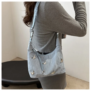 Détail du sac hobo bleu clair avec breloques papillon en argent sur tissu nylon