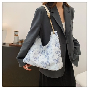 Borsa tote in peluche bianca con ricamo farfalla blu e tracolla a catena su modella