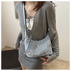 Détail du sac à bandoulière plissé argenté avec papillons métalliques et sangle réglable