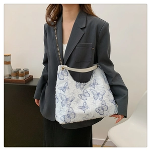 Detail of white plush tote bag with blue butterfly prints and metal chain handle