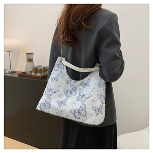 Detail of white butterfly tote bag featuring textured fabric and gold chain strap
