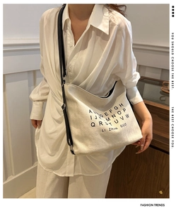 Close-up of minimalist canvas tote bag with letter print and black shoulder strap
