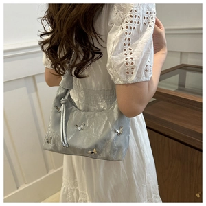 Détail du sac papillon argenté avec texture plissée et bandoulière à nœud élégant