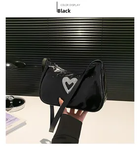 Detail of a black patent leather shoulder bag featuring a silver rhinestone heart cutout