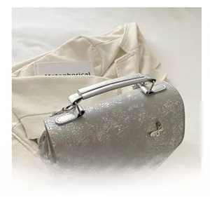 Detail of silver crossbody bag with 3D metal butterfly ornaments and texture