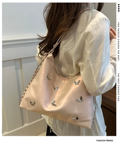 Detail of satin shoulder bag featuring 3D silver butterflies and metal chain strap