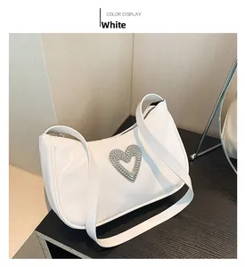 Detailed close-up of a white textured PU leather hobo bag with a silver crystal heart buckle
