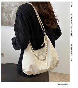Detail of off-white hobo bag showing wrinkled texture with silver chain and leather strap