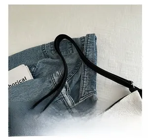 Detail of woven fabric shoulder bag with black faux leather strap and metal hardware