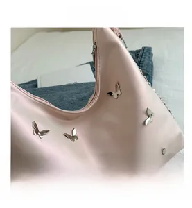 Detail shot of pink Hobo shoulder bag featuring decorative silver metal butterfly studs