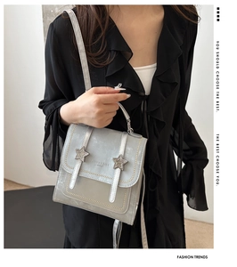 Detail of silver vintage backpack with star studs and leather handle on a black dress