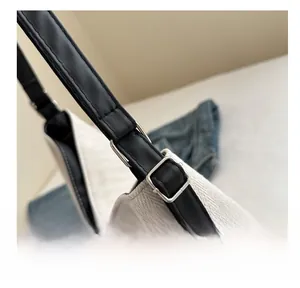 Detail of canvas shoulder bag with black leather strap and adjustable silver metal buckle