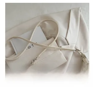 Close-up of cream shoulder bag with dual leather and woven metal chain straps