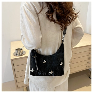 Détail du sac à bandoulière noir plissé avec papillons métalliques argentés