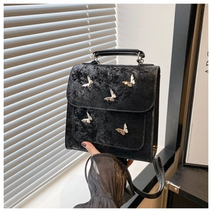 Detail of black faux leather bag with cracked texture and silver butterfly metal accents