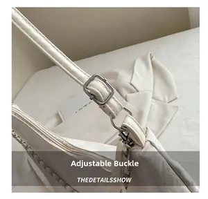 Detail view of adjustable silver buckle and metal chain strap on white tote bag