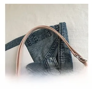 Detail of light pink tote bag handle with high-quality stitching on denim background