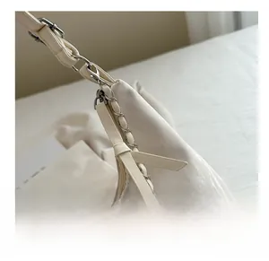 Detail view of silver chain strap and leather puller on ivory tote shoulder bag