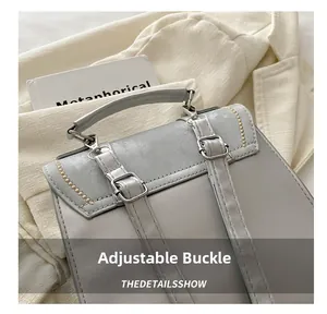 Close-up of adjustable silver buckle and yellow stitching on grey faux leather backpack