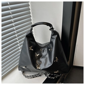 Detail of black Hobo bag with silver butterfly accents and woven chain strap