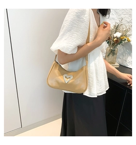 Detailed view of beige underarm bag featuring a large silver rhinestone heart buckle