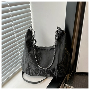 Detail of black pleated hobo bag with silver chain strap and vintage textured surface