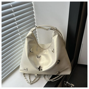 Detail of creamy white leather tote bag with silver butterfly charms and chain strap
