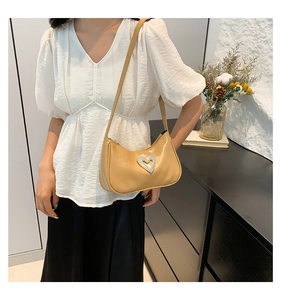 Detail view of khaki baguette shoulder bag with diamond heart on a model wearing white shirt