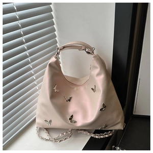 Detail of silver butterfly charms and chain strap on a pink satin tote bag
