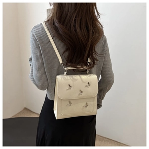 Detail of butterfly-embellished cream white crossbody bag with silver metallic accents