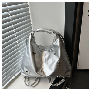 Detail of silver hobo bag featuring decorative 3D metal butterflies and chain strap