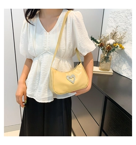 Detail of a beige patent leather hobo bag with a large sparkling rhinestone heart buckle