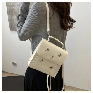 Detail of white PU leather crossbody bag featuring five silver metal butterfly ornaments