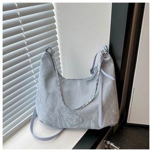 Close-up of light blue crescent bag with pleated texture and silver chain detail